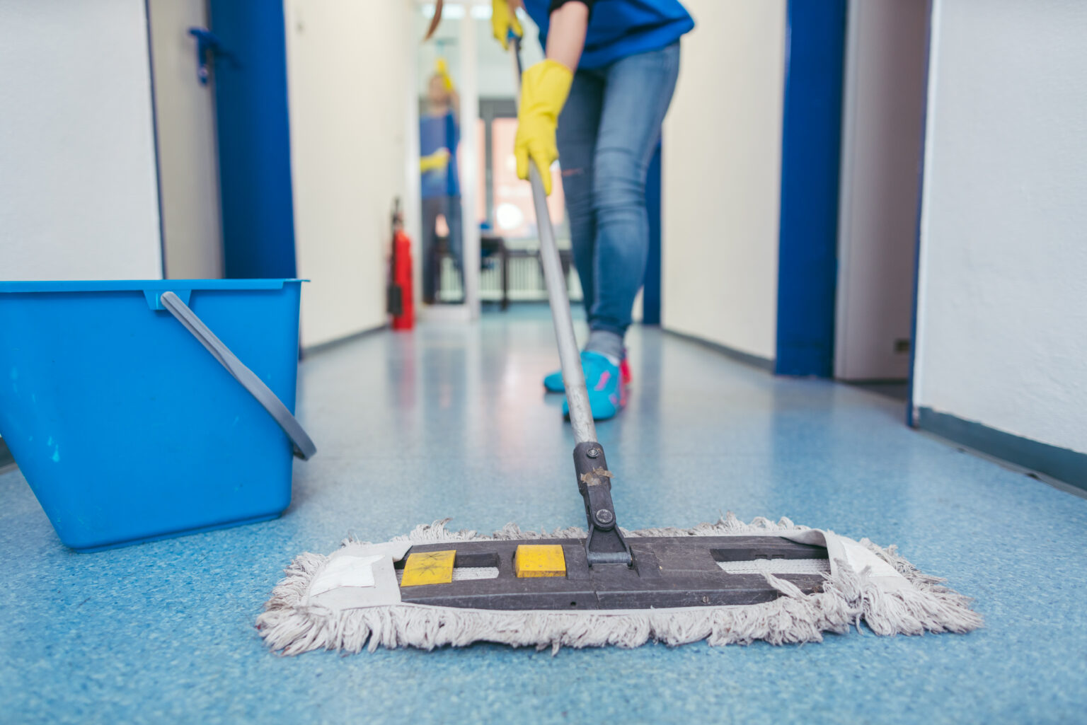 Close-up of cleaners moping the floor of a hall